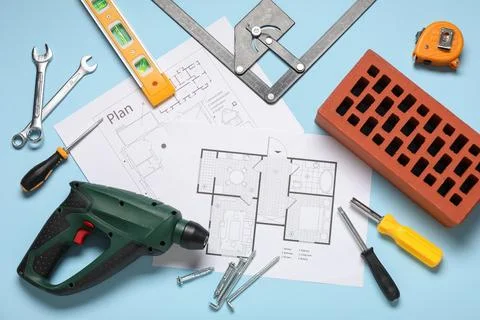 Different construction tools, brick and house plan on blue background Stock Photos