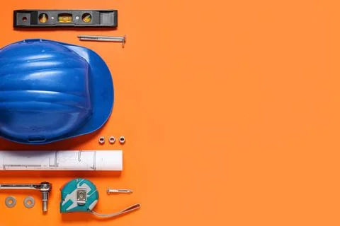 Different construction tools, hardhat and house plan on orange background Stock Photos