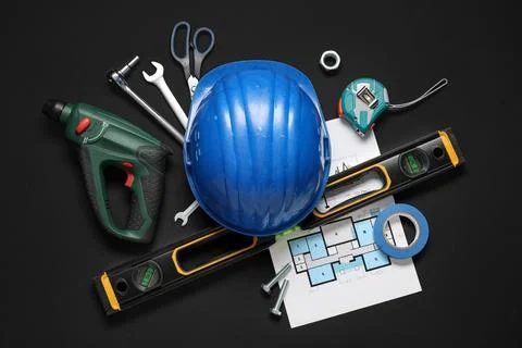 Different construction tools, hardhat and house plan on black background Stock Photos