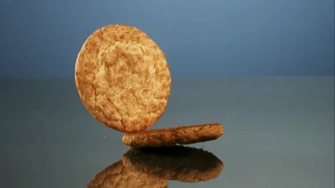Different cookies fall onto a dark blue reflective surface Stock Footage 327512391