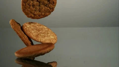 Different cookies falling on a gray reflective table Stock Footage 326750279