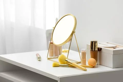 Different cosmetics and mirror on dressing table near white wall in room Stock Photos