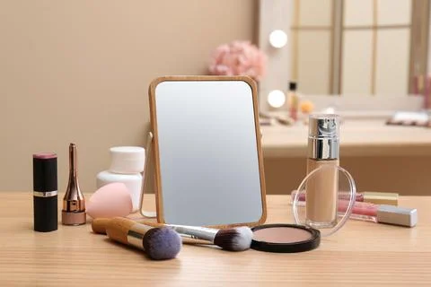 Different cosmetics, makeup brushes and mirror on table in living room, close Stock Photos
