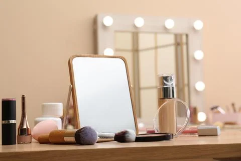 Different cosmetics, makeup brushes and mirror on table in living room, close Stock Photos