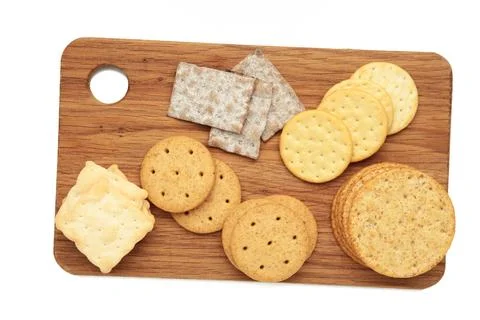 Different crackers on cutting board isolated on white background. Vertical .. Stock Photos