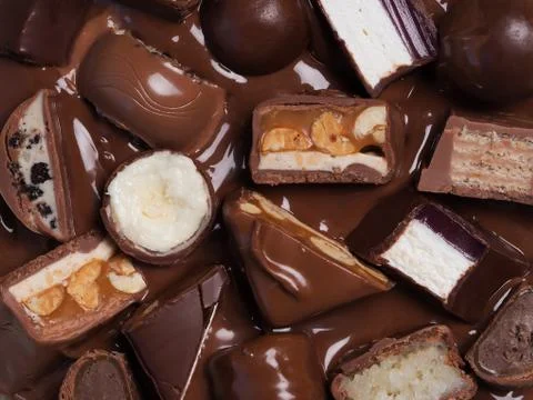 Different cut chocolate bars in melted chocolate, top ofview, close-up. Stock Photos