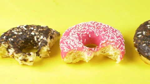 Different delicious colored bites donuts on yellow background Stock Footage 149479257