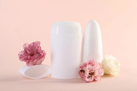 Different deodorants and beautiful eustoma flowers on beige background 스톡 사진