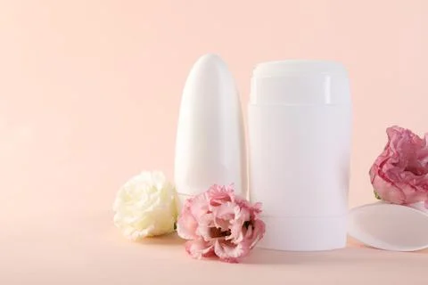 Different deodorants and beautiful eustoma flowers on beige background 스톡 사진