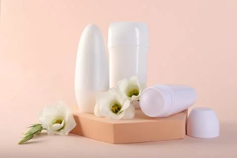 Different deodorants and beautiful eustoma flowers on beige background 스톡 사진