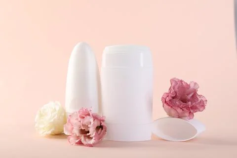Different deodorants and beautiful eustoma flowers on beige background 스톡 사진