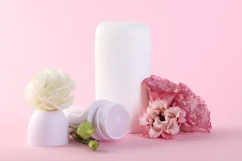 Different deodorants and beautiful eustoma flowers on pink background 스톡 사진