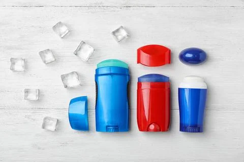 Different deodorants and ice cubes on light wooden background Foto stock