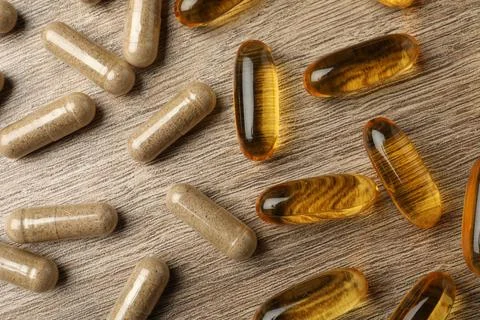 Different dietary supplements capsules on wooden table, flat lay Stock Photos