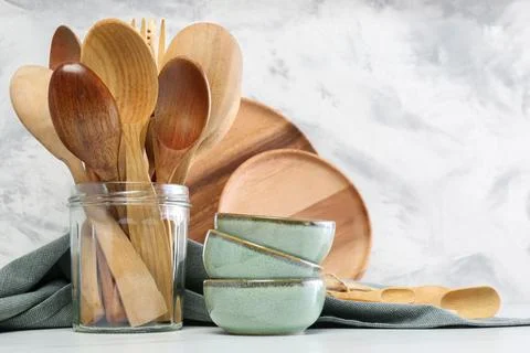 Different dishware and utensils on white marble table against textured wall Stock Photos