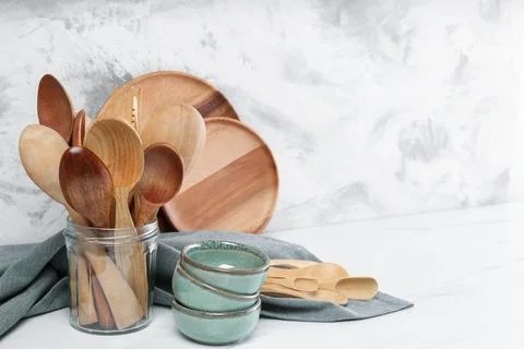 Different dishware and utensils on white marble table against textured wall.. Stock Photos