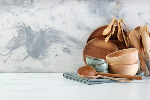 Different dishware and utensils on white marble table against textured wall.. Stock Photos