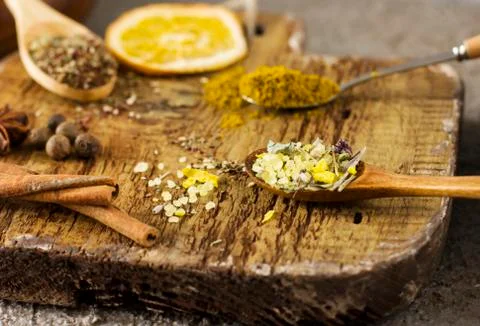 Different dry spices in spoons on old wooden board Stock Photos