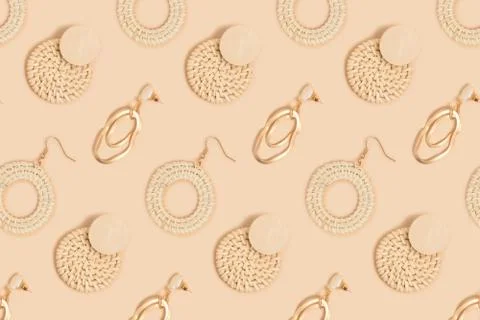 Different earrings pattern on a beige background. Stock Photos