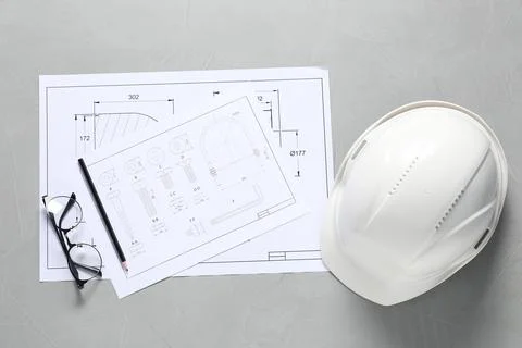 Different engineering drawings, hard hat, pencil and glasses on grey table,.. Stock Photos