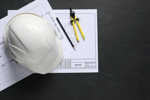 Different engineering drawings, pencil, divider and hard hat on black table.. Stock Photos