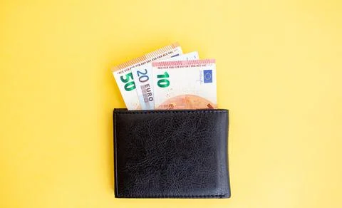 Different euro banknotes inside a black wallet on yellow background Stock Photos