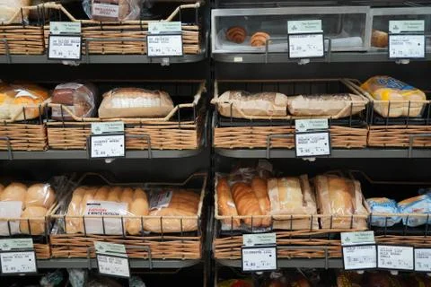 Different fresh bread on the shelves in bakery. Interior of a modern grocery Stock Photos