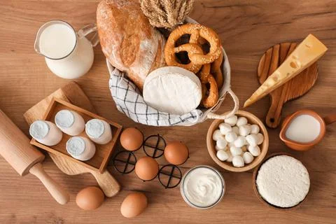 Different fresh dairy products with bread on table in kitchen, top view Stock Photos