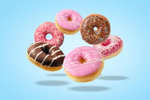Different fresh donuts on blue background. Minimal food concept. Stock Photos