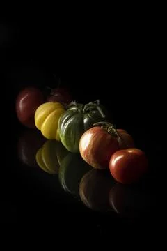 Different fresh tomatoes on a black table Stock Photos