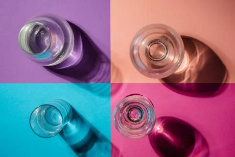 Different glasses of water stand on multi-colored paper Stock Photos