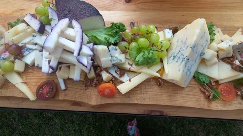 Different grade sliced cheese, bunches of grapes and lettuce lies on table. Stock-Footage 199034709
