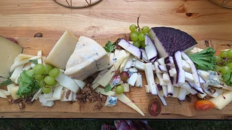 Different grade sliced cheese, bunches of grapes and lettuce lies on table Stock Footage 199034750