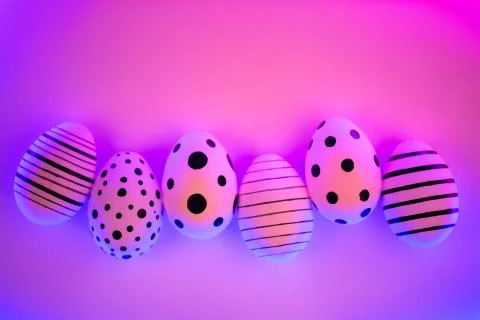 Different graphic hand-painted eggs in Proton Purple neon light. Stock Photos