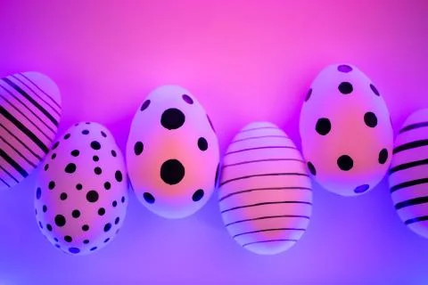 Different graphic hand-painted eggs in Proton Purple neon light. Stock Photos
