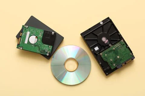 Different hard drives and CD disk on beige background Stock Photos