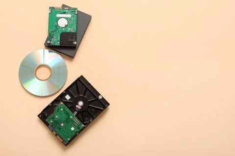 Different hard drives and CD disk on beige background Stock Photos
