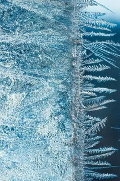 Different ice frost pattern on glass, winter blue background Stock Photos