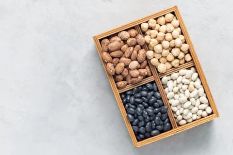 Different kinds of beans: black, pinto, white and chickpeas in wooden box on Foto stock