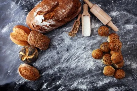 Different kinds of bread and bread rolls on black board. Kitchen or bakery po Stock Photos