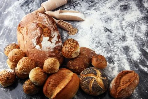 Different kinds of bread and bread rolls on black board. Kitchen or bakery po Foto stock