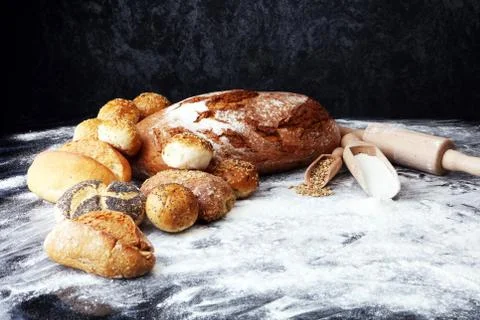 Different kinds of bread and bread rolls on black board. Kitchen or bakery po Stock Photos