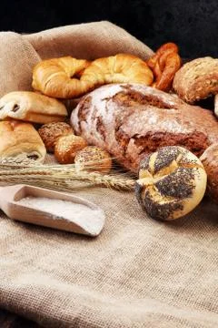 Different kinds of bread and bread rolls on burlap sack. Kitchen or bakery po Stock Photos