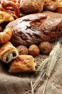 Different kinds of bread and bread rolls on burlap sack. Kitchen or bakery po Stock Photos