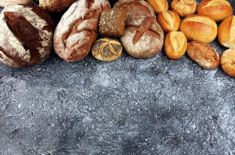 Different kinds of bread and bread rolls on board from above. Kitchen or bake Stock Photos