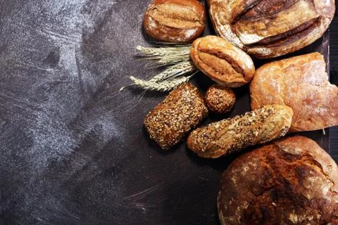 Different kinds of bread and bread rolls on board from above. Kitchen or bake Stock Photos