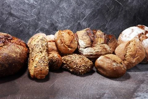 Different kinds of bread and bread rolls on board from above. Kitchen or bake Stock Photos