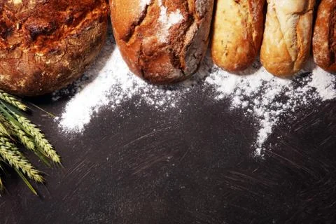 Different kinds of bread and bread rolls on board from above. Kitchen or bake Stock Photos