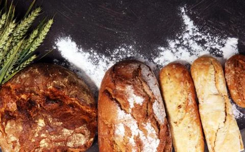 Different kinds of bread and bread rolls on board from above. Kitchen or bake Stock Photos