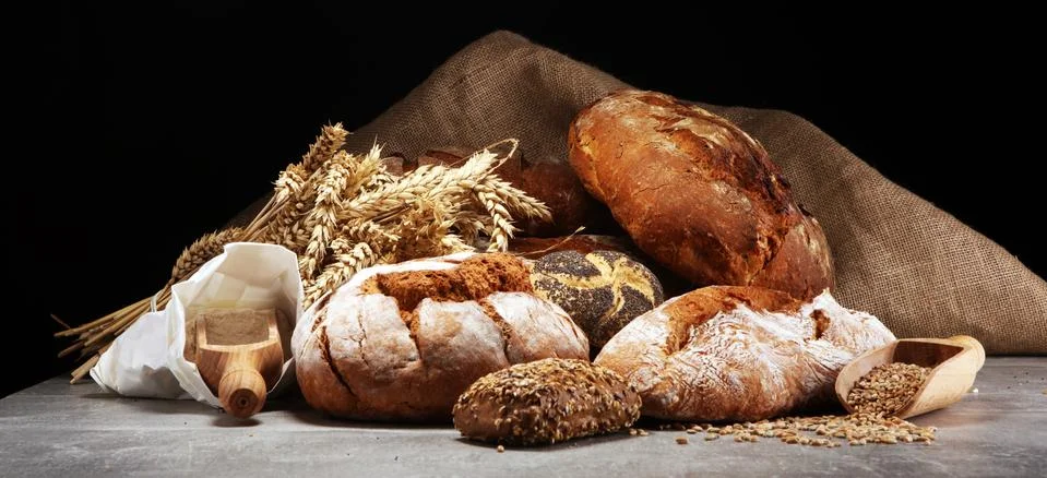 Different kinds of bread and bread rolls on board from above. Kitchen or bake Stock Photos